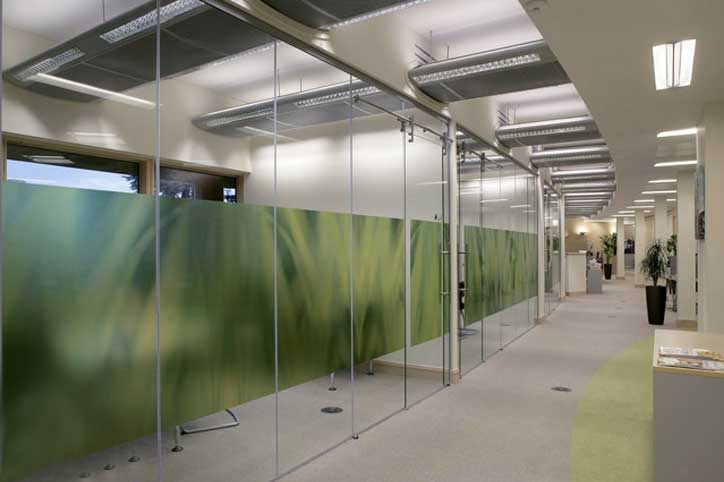 A room with glass walls and green leaves on the wall.