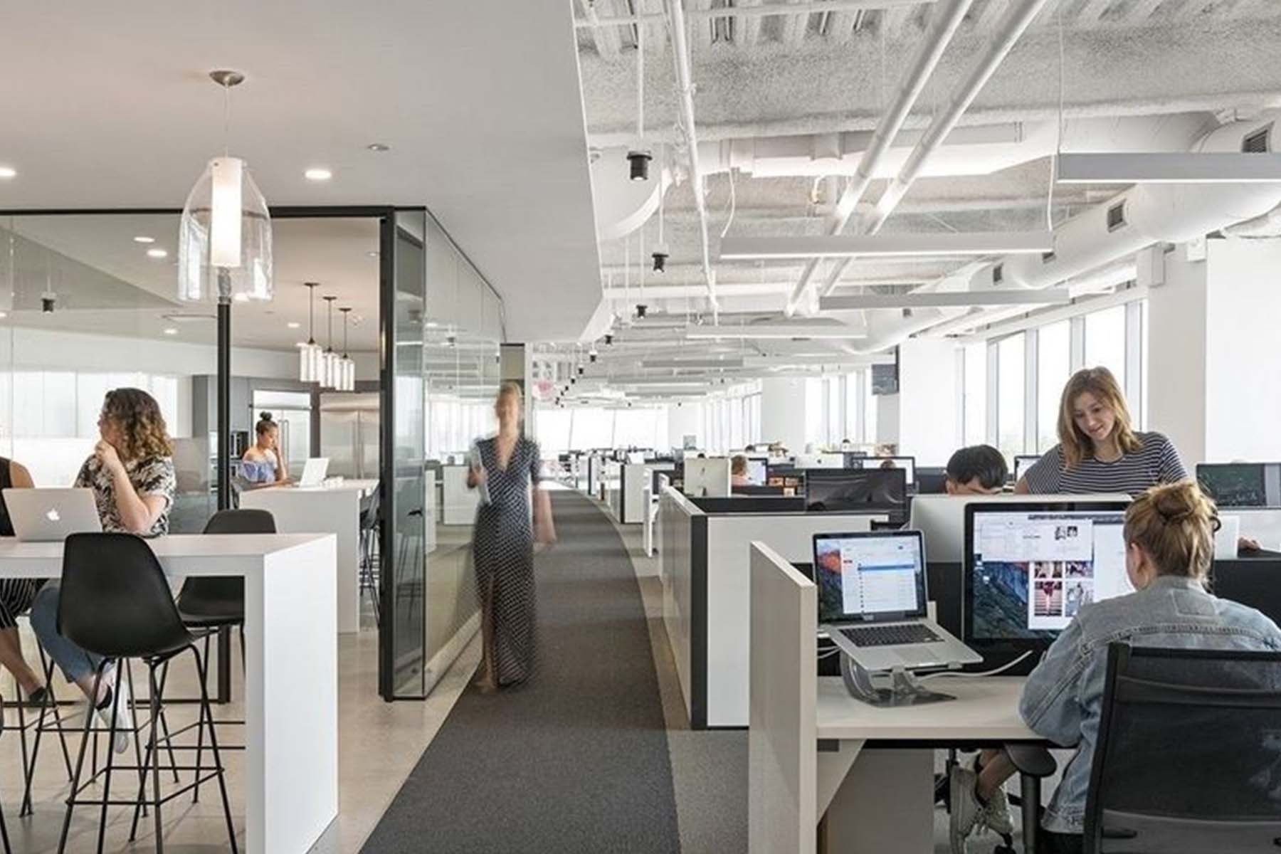 A large open office with people working on laptops.